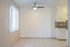Inviting space with sleek tiled flooring, modern ceiling fan, and adjacent kitchen featuring elegant cabinetry and backsplash.