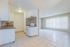 Bright open-plan living space with a modern kitchen featuring sleek white cabinets, a stylish backsplash, and abundant natural light.