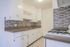 Charming kitchen boasting modern cabinetry, sleek countertops, and an elegant tiled backsplash, perfect for culinary adventures.