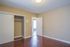 Bright and inviting bedroom with sleek hardwood floors, spacious closet, and warm neutral walls, perfect for a cozy retreat.