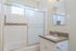 Bright, modern bathroom featuring sleek shower doors, elegant tile accents, and a stylish vanity with ample light.