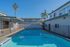 Charming residential swimming pool area surrounded by palm trees and modern buildings under a clear blue sky.