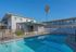 Sunny apartment complex featuring a refreshing swimming pool and modern architecture, perfect for relaxed living.