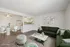 Chic and modern open-plan living room with plush green sofas, stylish decor, and a cozy dining area adjacent to a contemporary kitchen.