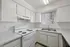 Bright and modern kitchen featuring sleek white cabinetry, granite countertops, and a double sink with a view of the outdoors.