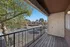 Charming apartment balcony with a wooden deck, overlooking a serene neighborhood with lush trees and parked cars.