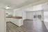 Inviting open-plan apartment with sleek flooring, bright kitchen, and large sliding doors to a sunlit patio.