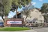 Inviting entrance to Emerald Bay Apartments framed by lush greenery and elegant stone sign, showcasing a serene and welcoming residential community.
