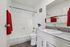 Bright and modern bathroom featuring white fixtures, sleek countertop, and a touch of elegance with vibrant red towels.