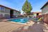 Inviting apartment complex with a sparkling outdoor swimming pool, surrounded by lounge chairs and lush greenery, perfect for relaxation and entertainment.