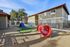 Inviting apartment exterior with a vibrant children's play area, featuring a colorful slide and tunnel set against a backdrop of manicured greenery and modern architecture.