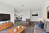 Bright and modern living area with sleek furnishings, large TV, and stylish decor, leading to a chic dining space perfect for entertaining.