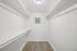 Spacious walk-in closet with sleek white shelving and elegant wooden flooring, perfect for organized living.