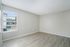 Bright empty room with large window, light wood flooring, and neutral walls offering a versatile space to personalize.