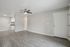 Chic modern living area with sleek hardwood flooring and a built-in ceiling fan, featuring an open layout leading to a stylish kitchen with contemporary white cabinetry.