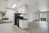 Bright open-plan kitchen and living area with sleek black appliances, elegant countertops, and stylish ceiling fan. Perfect for modern living.