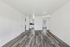 Bright and airy open-concept living space with modern gray flooring and sleek white walls, leading into a cozy kitchen area.
