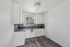 Chic modern kitchen with sleek white cabinetry, elegant dark countertops, and a stylish backsplash, offering a bright and refreshing atmosphere.