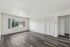 Bright and spacious empty room with elegant wood-style flooring, large window, and neutral white walls.