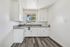 Charming, bright kitchen with modern white cabinetry, sleek gray countertops, and a cozy window view.