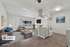 Contemporary open-plan living room and kitchen with cozy seating area, bright windows, and sleek modern decor.