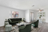 Elegant living room with plush green velvet seating, stylish glass coffee table, and modern dining area, showcasing a serene and inviting ambiance.