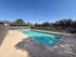 Refreshing outdoor swimming pool with clear blue water, surrounded by a secure fence and shaded seating area, perfect for relaxation and leisure in a serene residential setting.