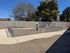 Charming outdoor space with fenced garden area, surrounded by mature trees under a bright blue sky.