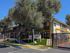 Inviting two-story apartment building with lush trees and secured gated entrance, perfect for comfortable living.