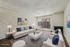 Modern living room with stylish furniture, vibrant wall art, and floor-to-ceiling windows offering abundant natural light.