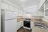 Charming kitchen featuring white cabinetry, sleek granite countertops, and modern appliances including a spacious fridge and gas stove.