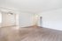 Bright and airy living space with sleek wood flooring, an elegant ceiling fan, and ample natural light flowing into the open kitchen area.
