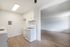Inviting kitchen space with sleek white cabinets, modern gas stove, and elegant wooden flooring opening into a spacious living area.