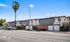 Charming two-story apartment complex with a modern exterior featuring red brick, green landscaping, and convenient parking under a clear blue sky.