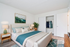 Bright and inviting bedroom with elegant decor, featuring a cozy bed with plush pillows, stylish nightstands, and a vibrant green plant. Modern sliding closet offers ample storage space.