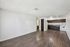 Spacious open living area with elegant wood flooring and a modern kitchen featuring dark cabinetry and white appliances.