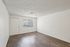 Bright and airy room with elegant wood flooring, modern white walls, and ample natural light from a large window.