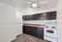 Modern kitchen with sleek dark cabinets, white appliances, and stylish wooden flooring.
