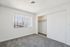 Bright and airy bedroom with plush carpeting, large window with vertical blinds, and spacious closet with sliding doors.