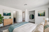 Elegant bedroom with cozy bedding, stylish wooden dresser, and spacious closet, enhanced by tasteful artwork and lush greenery.