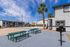 Inviting outdoor space featuring picnic tables, a barbecue grill, and vibrant palm trees under a clear blue sky, ideal for leisurely gatherings.