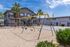 Inviting apartment courtyard with modern swing set, lush palm trees, and sunny skies.