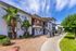 Charming apartment complex with lush palm trees and a vibrant exterior, featuring spacious balconies and inviting walkways.