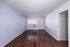Contemporary apartment interior featuring sleek hardwood floors, softly textured walls, and natural light streaming through a large window.