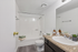 Modern bathroom with sleek design featuring a pristine white bathtub, elegant vanity with granite countertop, and stylish decor accents.