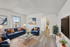 Modern living room with elegant decor, featuring blue seating, copper accents, and bright natural light.