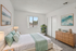Bright and inviting bedroom with modern decor, featuring a comfortable bed, stylish artwork, and a touch of greenery for a relaxing atmosphere.