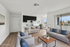 Modern and bright living space featuring an open-plan kitchen with sleek countertops, cozy seating area, and large windows offering ample natural light.