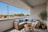 Charming outdoor balcony with cozy wicker seating, soft blue cushions, and a stylish coffee table, offering a relaxing spot with scenic views.