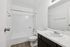 Modern bathroom with sleek white fixtures, a spacious bathtub, and elegant wood flooring, offering a serene retreat.